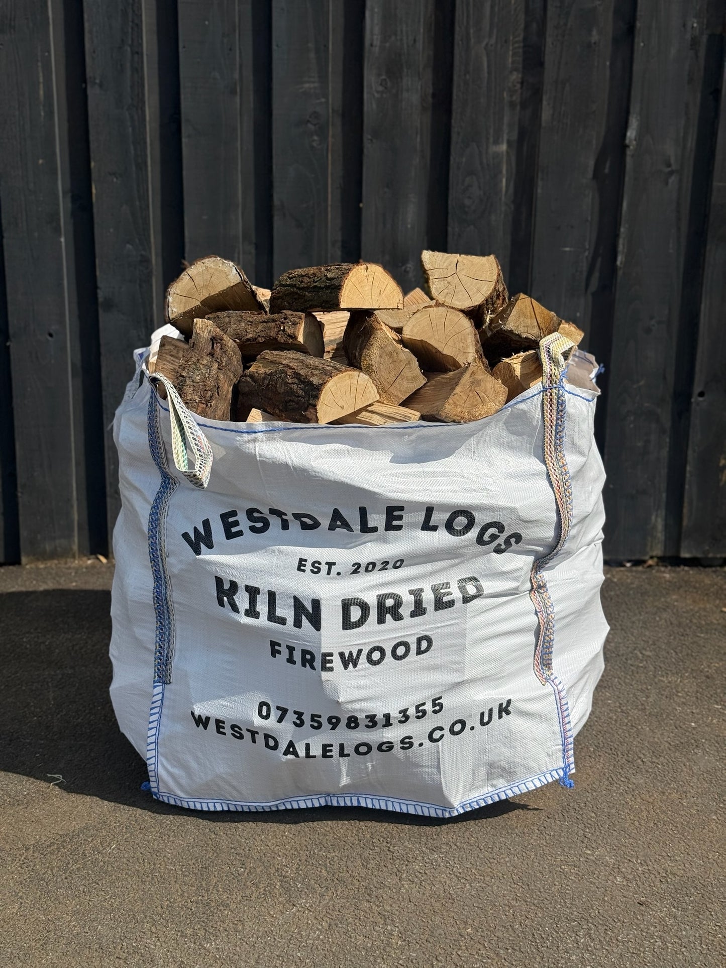 Bag of kiln dried oak firewood with Westdale Logs branding against a wooden background