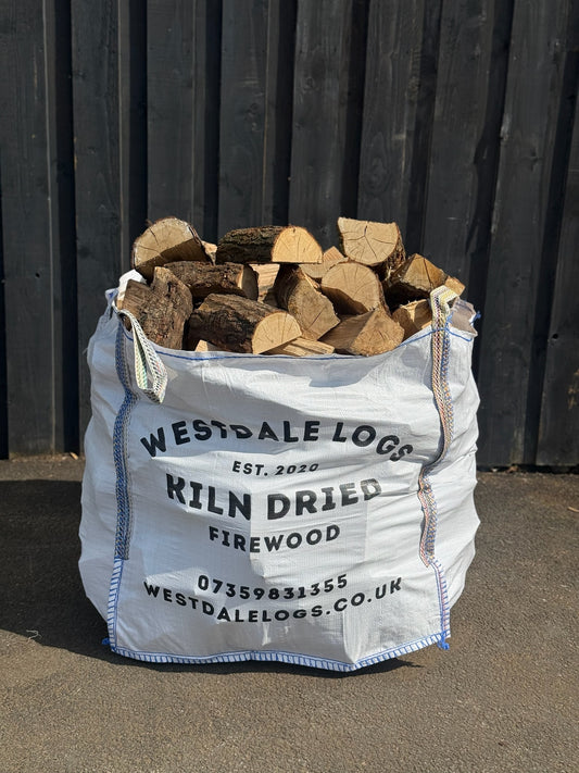 Kiln Dried Oak logs in a bulk bag on tarmac against a wooden clad wall